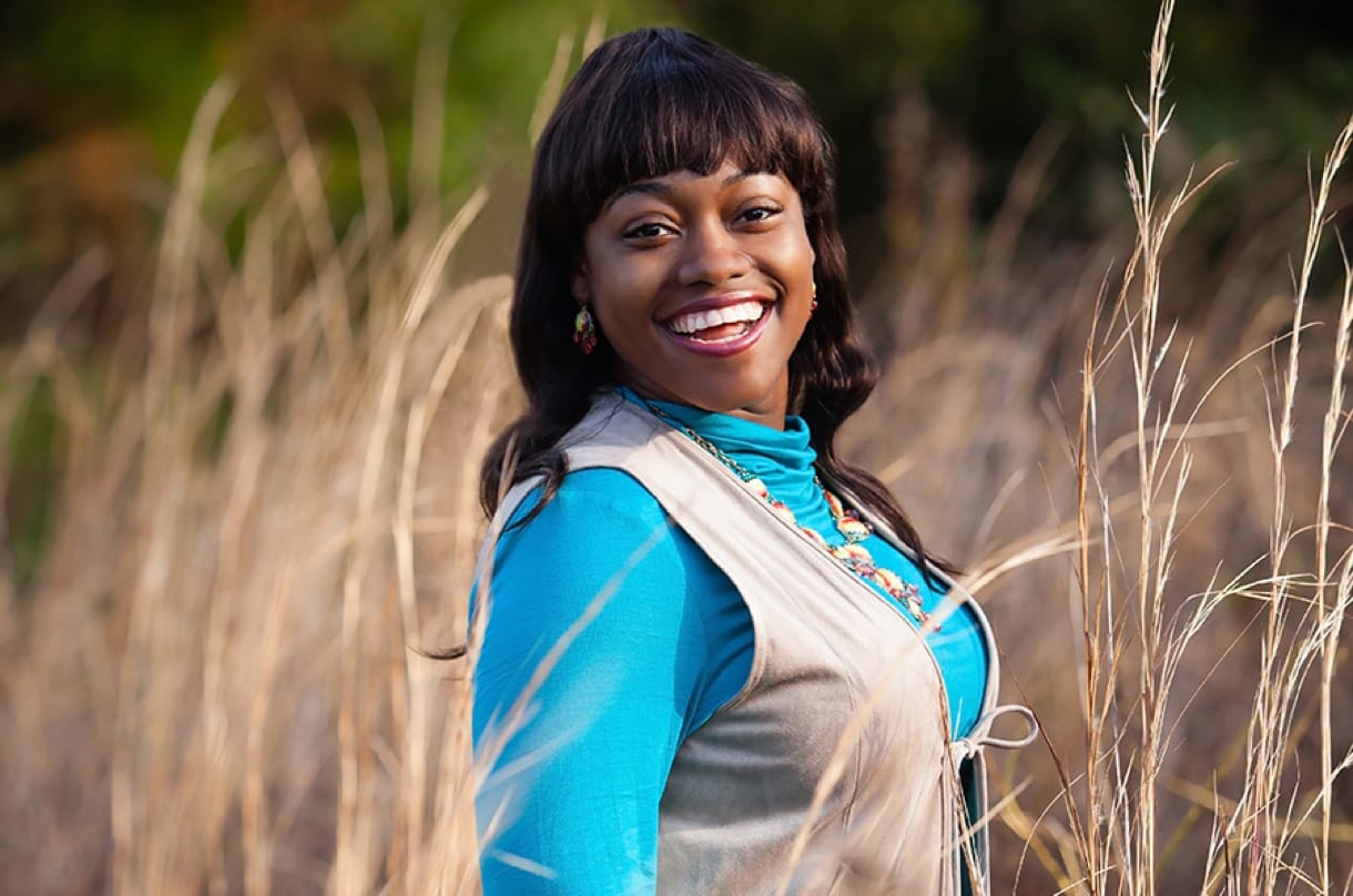Portrait photography shot of a young black woman smiling in a field