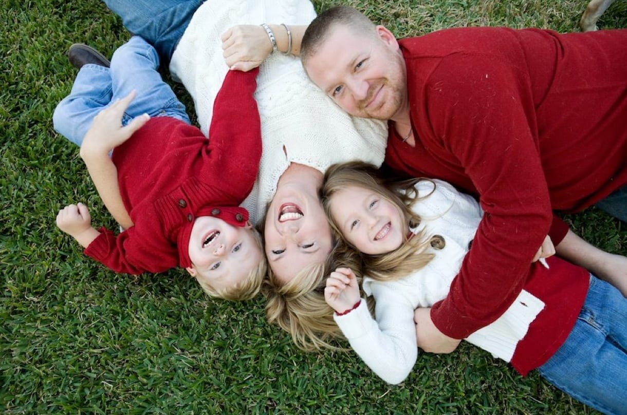 Family photography shot of husband, wife & two kids on the grass