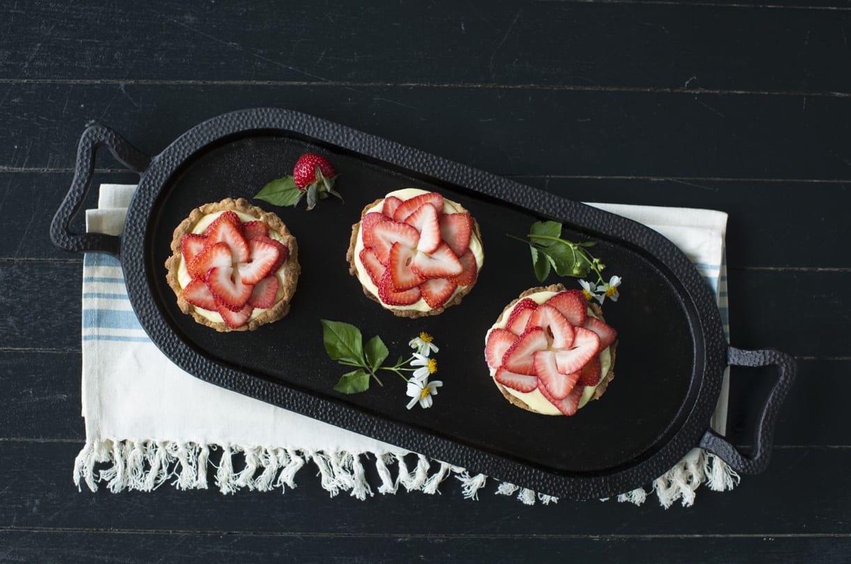 Food photography shot of strawberry cream tarts on a black skillet